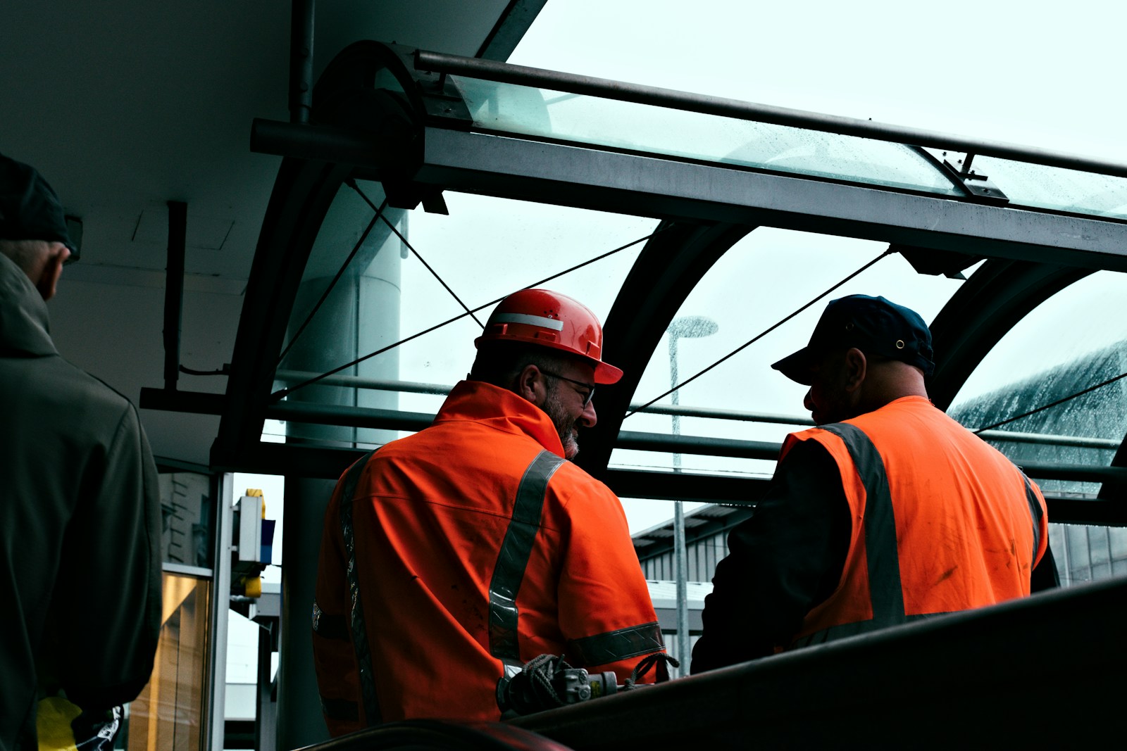 Two construction workers in orange vests talking